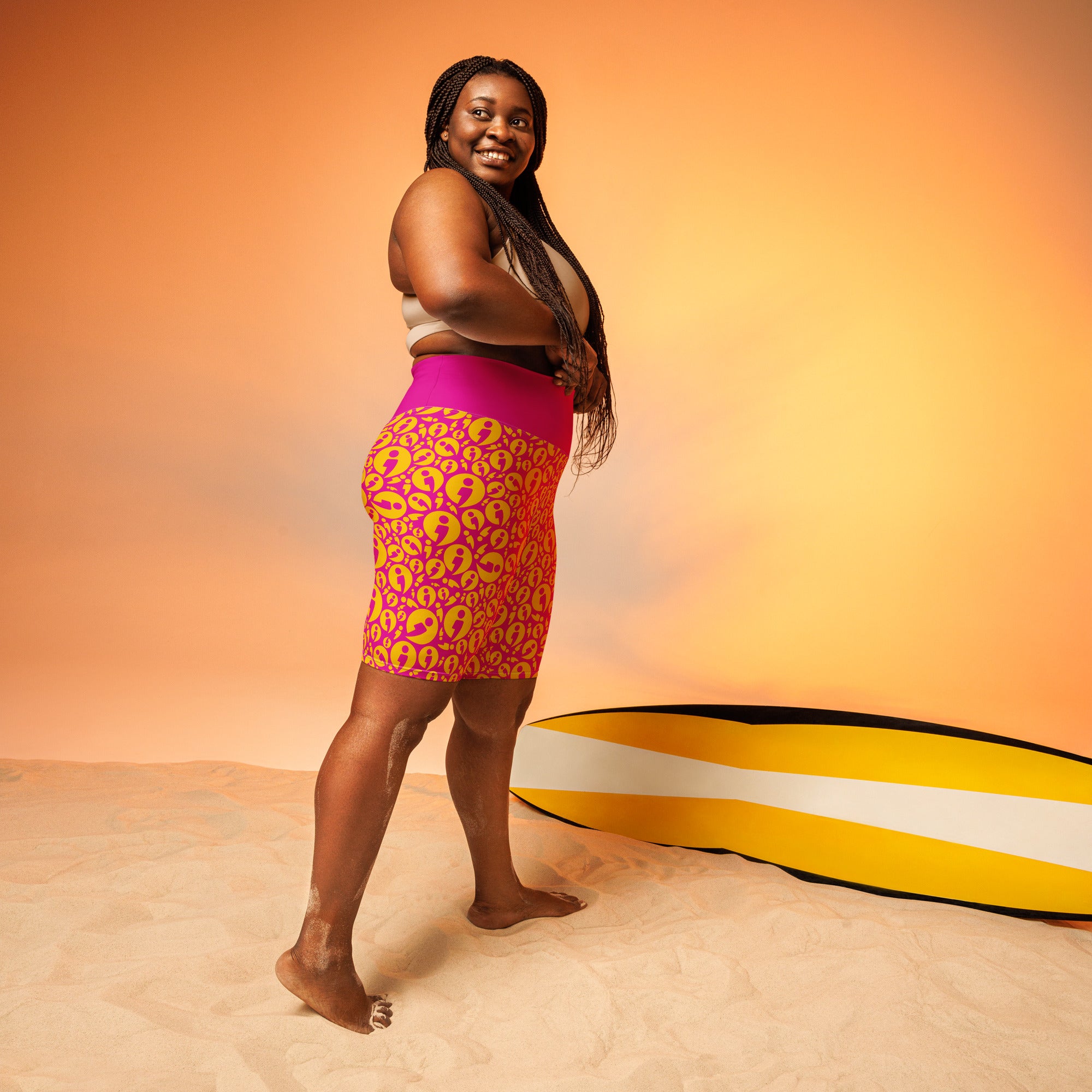 Model wearing pink patterned shorts standing with her body facing to the right and looking over her right shoulder
