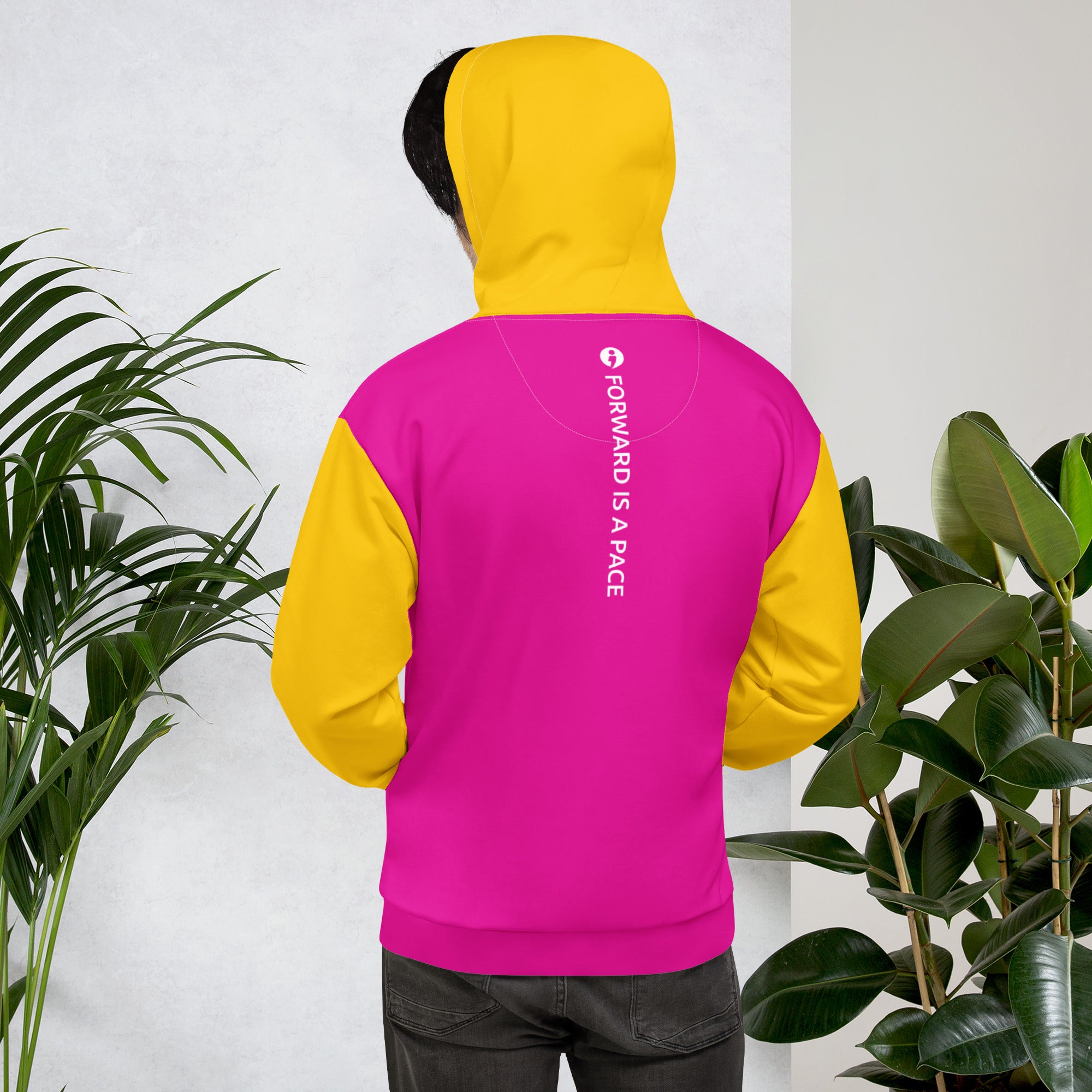 A person wearing the The Movement Collection unisex hoodie in Pink with their back facing displaying "Forward is a Pace" vertically down the middle of the back of the hoodie.