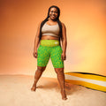 Model wearing green patterned shorts standing with her feet apart smiling at the camera.