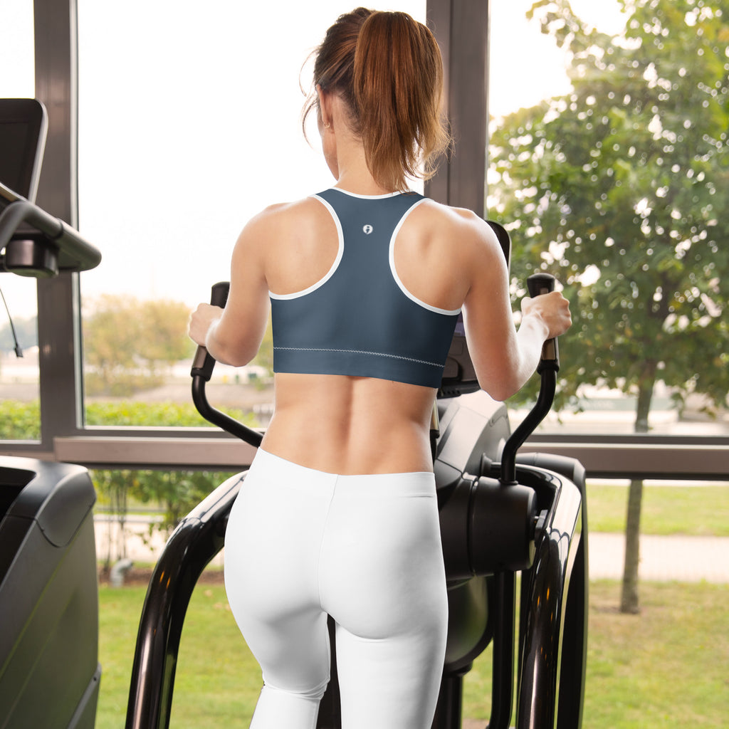 Woman exercising on a machine wearing a black and white striped sports bra with Still I Run sports bra on facing away from the camera, showing the back design that has the Still I Run semi-colon avatar between the shoulder blades.